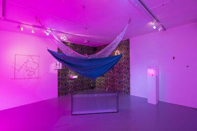 installation avec ambiance lumineuse fuschia, hamac et divers objets