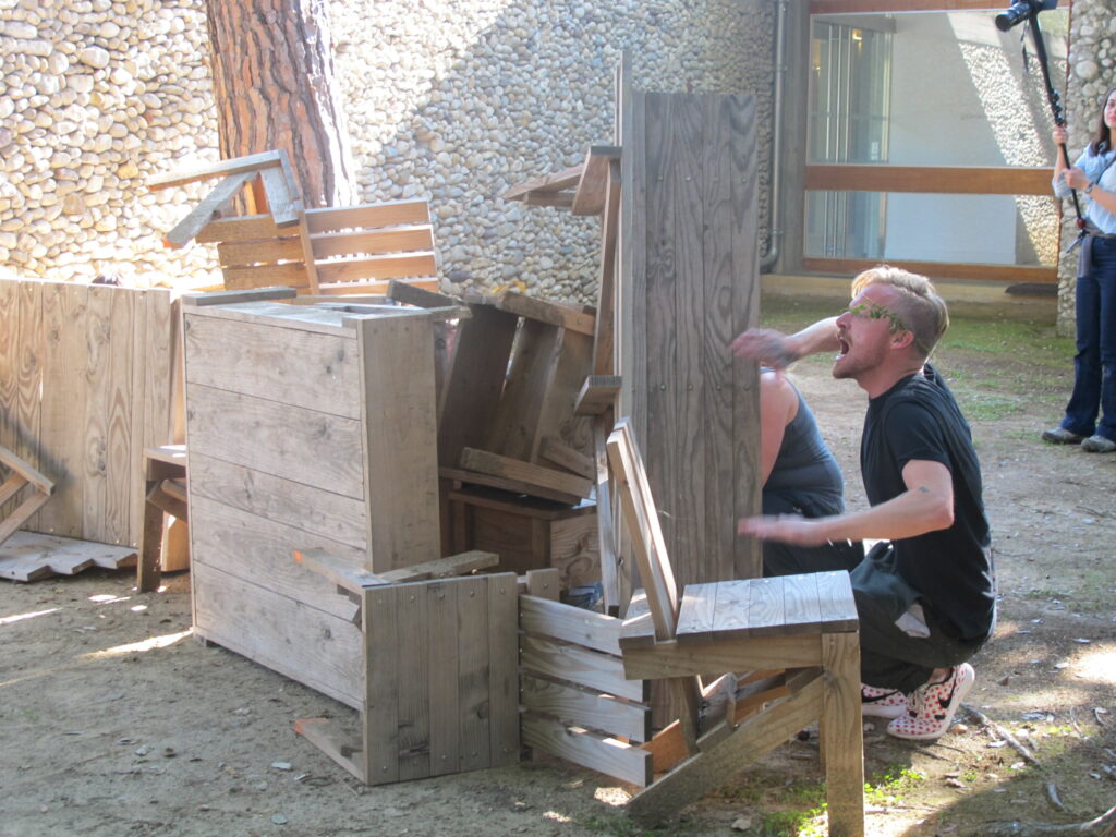 Une personne est caché derrière un amoncellement de mobilier en bois