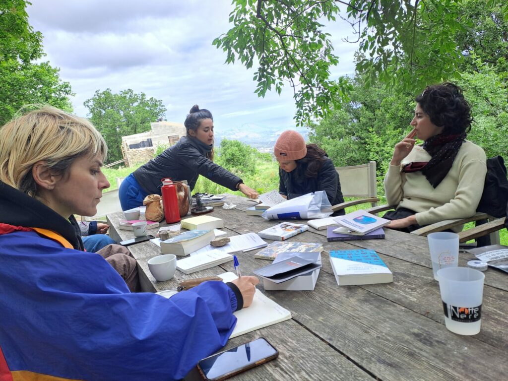 Des livres sur une table de bois en extérieur, des personnes autour