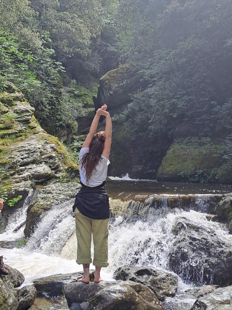 Une personne de dos devant une cascade
