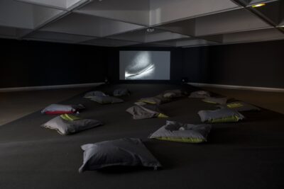salle plongée dans l'obscurité. Coussins au sol. écran vidéo.