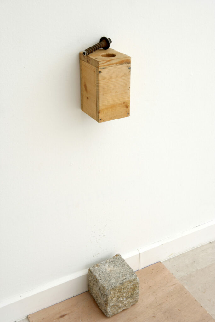 boîte en bois avec fond troué, boulon métallique, pavé de Paris